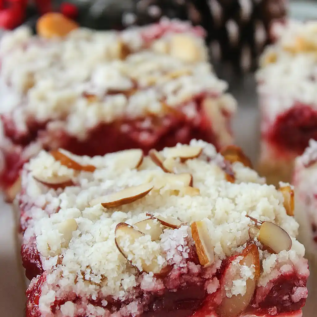 Modern Christmas cheesecake bars with vibrant cranberry swirl on white marble