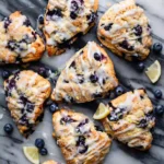 An elegant clay platter holding an anti-inflammatory scone glazed lemon blueberry on a white marble background.
